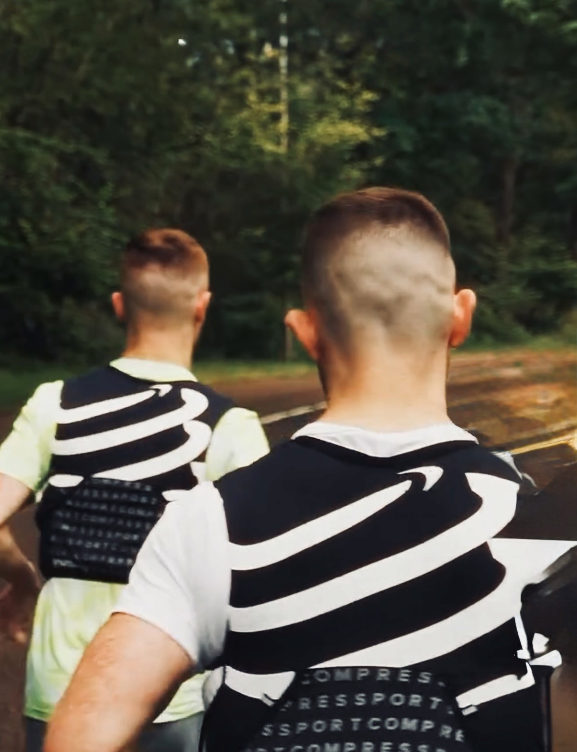 Two young athletes wearing Nike sportswear running outdoors during a Run Club photoshoot.