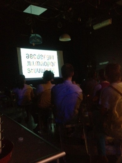 dark classroom with people seated and typography projected on screen