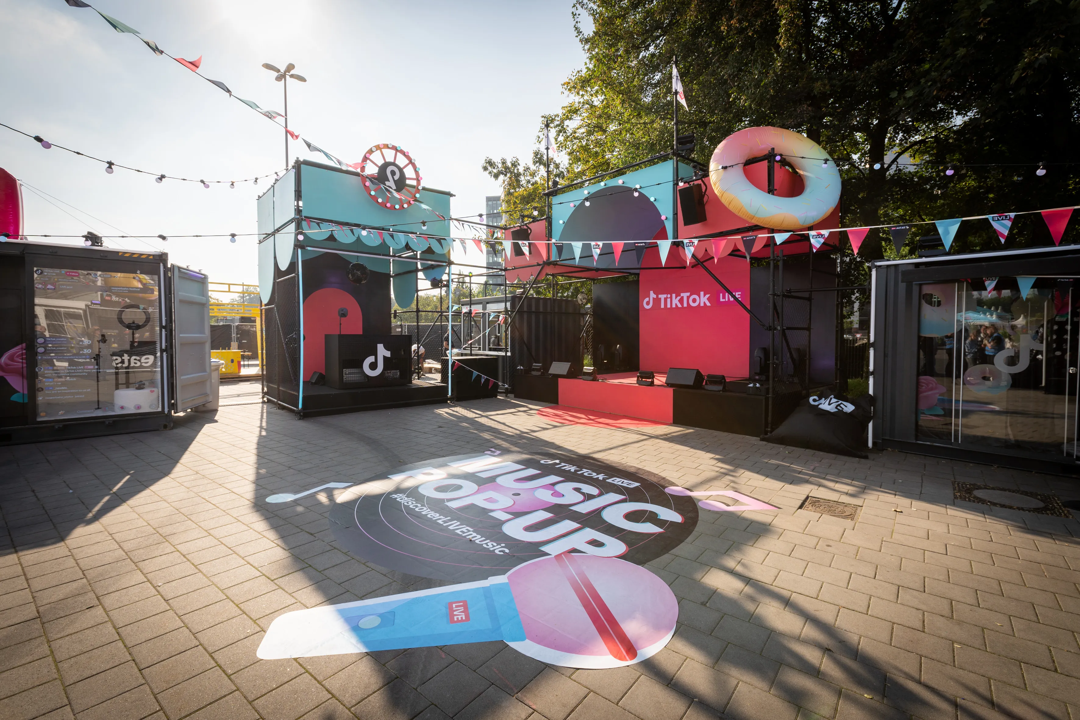 TikTok Music Pop-Up courtyard with container stages, donut sculpture and floor sticker.