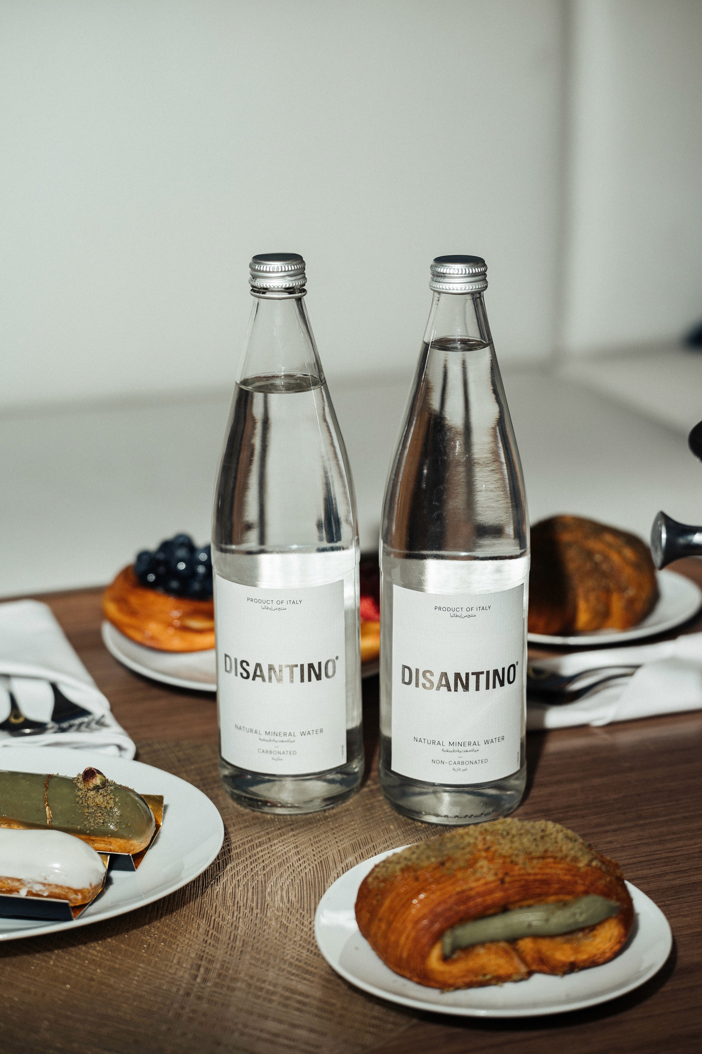Two bottles of DISANTINO mineral water accompanied by a variety of pastries.
