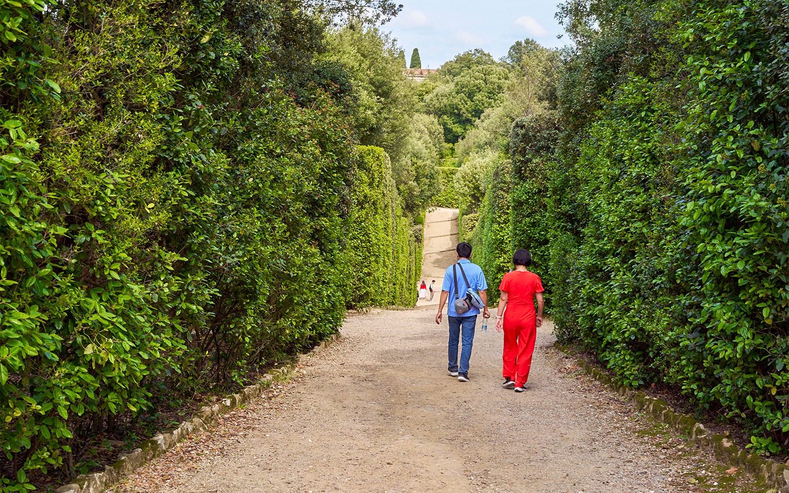Tourists walking through lush greenery in Boboli Gardens, Florence, Italy.