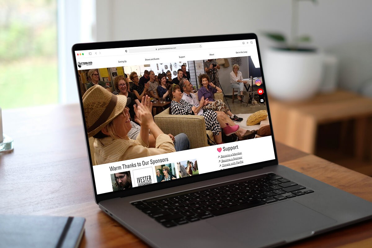 A mockup for a Macbook place on a table for a talk show website