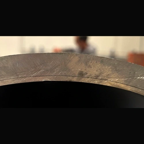 Close-up view of a metal pipe with a curved surface. A thin line is drawn on the surface.