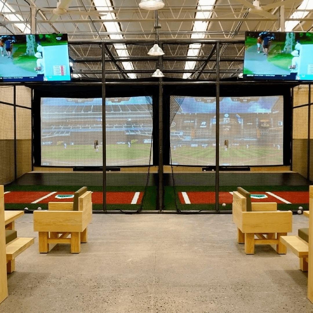 Interior view of the HitTrax Suite at Kingpin Social showing batting mat, netting, and simulator screen.