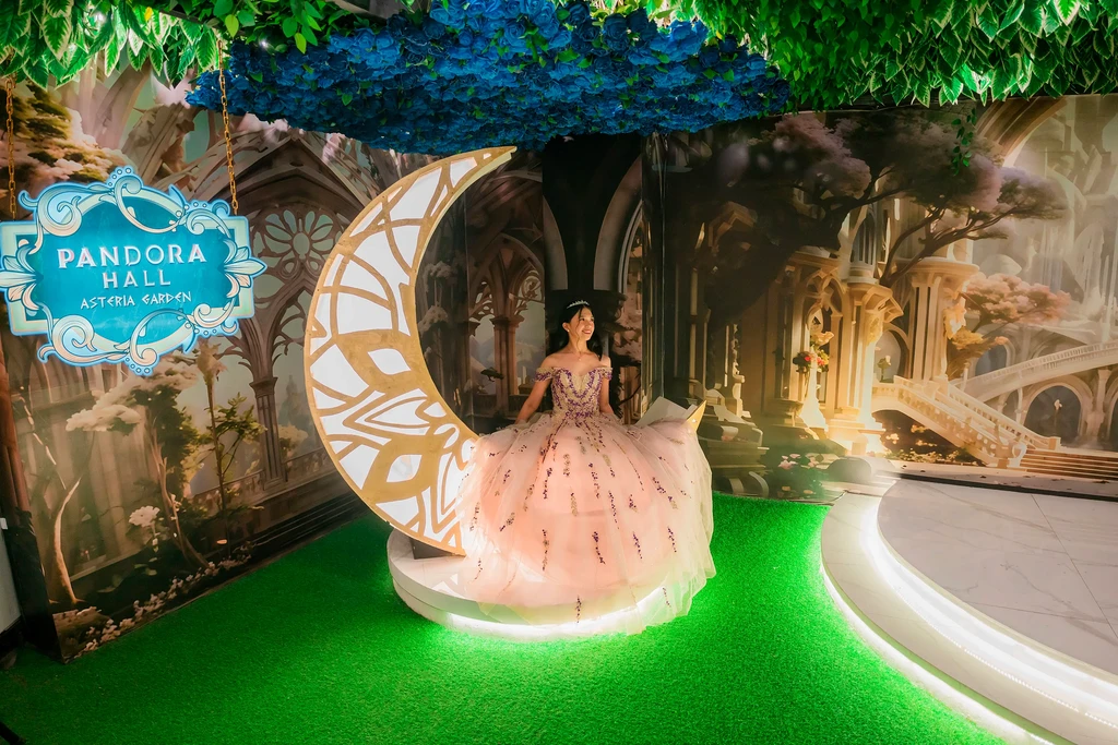 Debutante in a peach gown resting on the glowing crescent moon at Pandora Hall