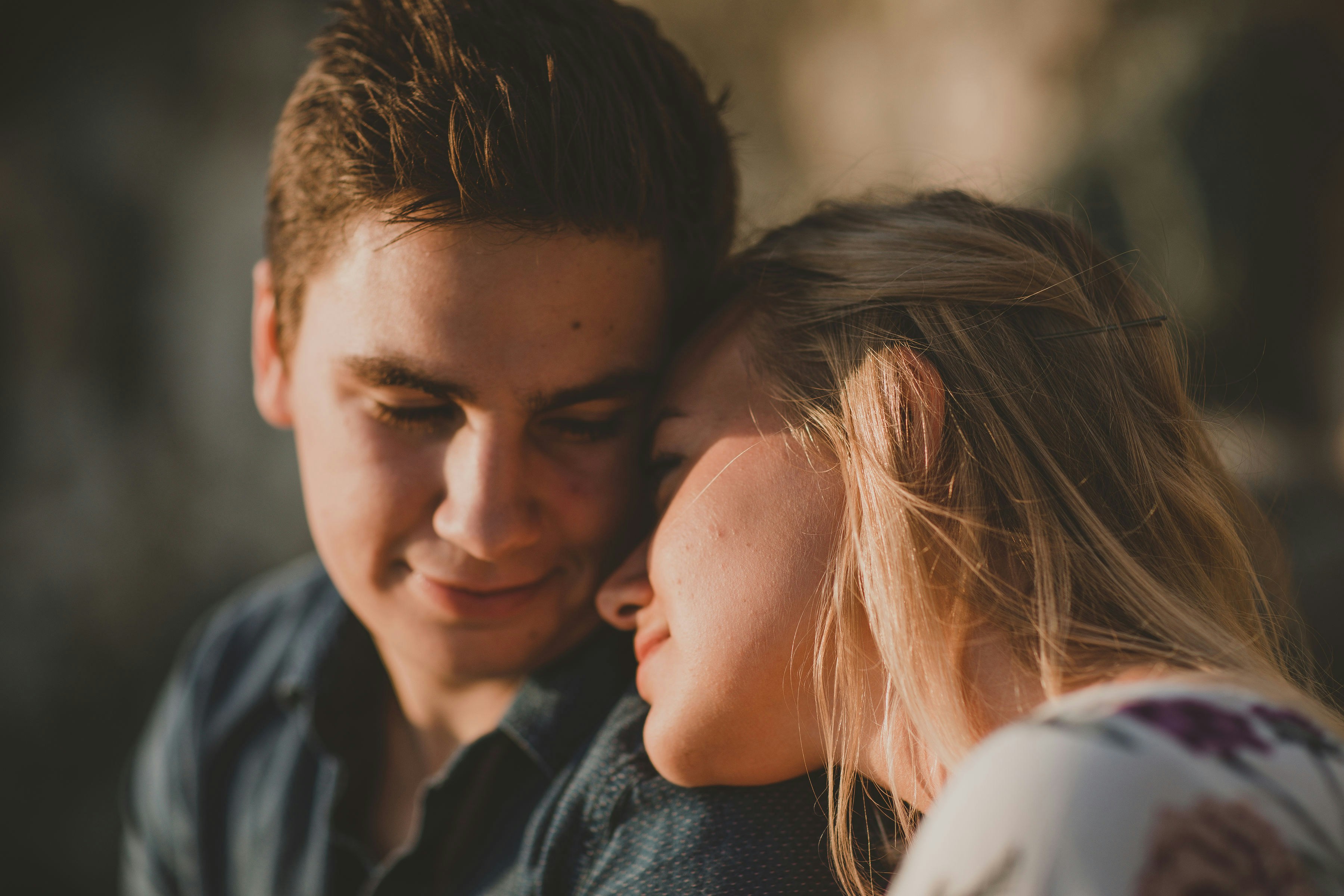 A couple sits close together, with the woman resting her head on the man's shoulder affectionately.