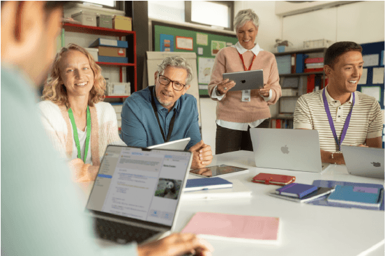 Gruppe von Lehrkräften arbeitet gemeinsam an MacBooks und iPads in einem Schulungsraum