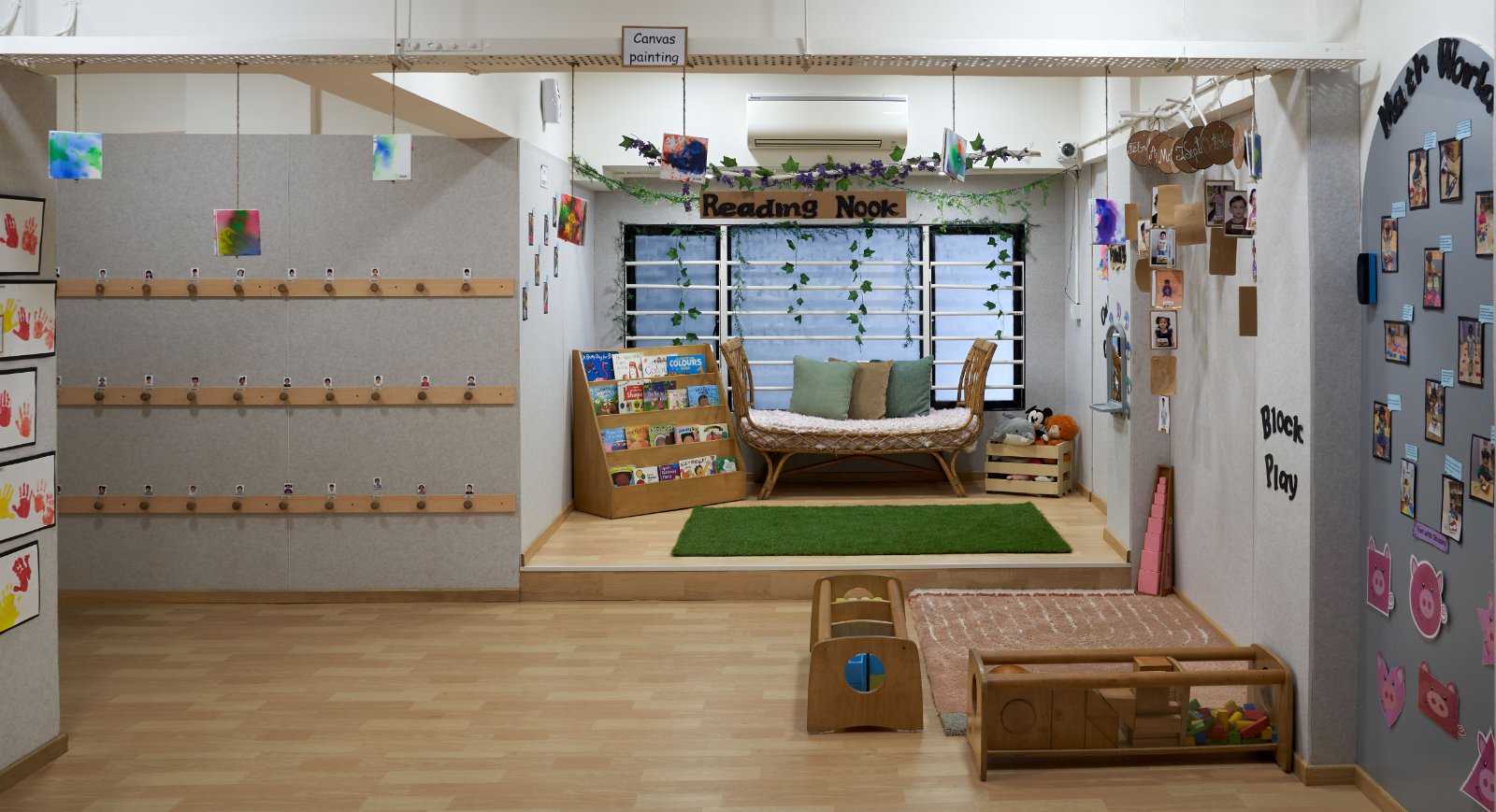 Nature-inspired preschool entrance with sculptural tree partitions and suspended green leaf ceiling panels.