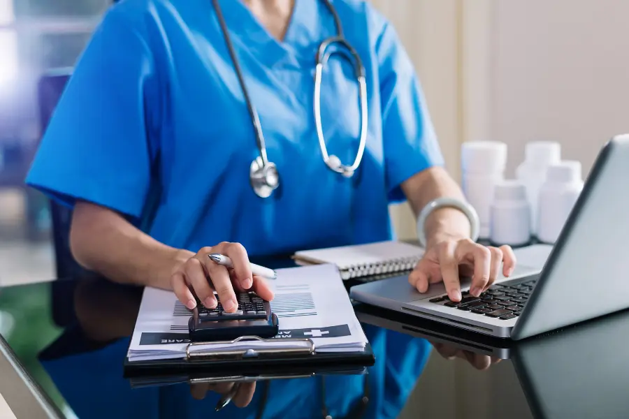 Artificial intelligence in pharmaceuticals illustrated by a nurse using a calculator and laptop near medication bottles.