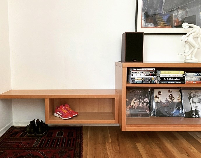 A detail of a wooden hanging cabinet with books.