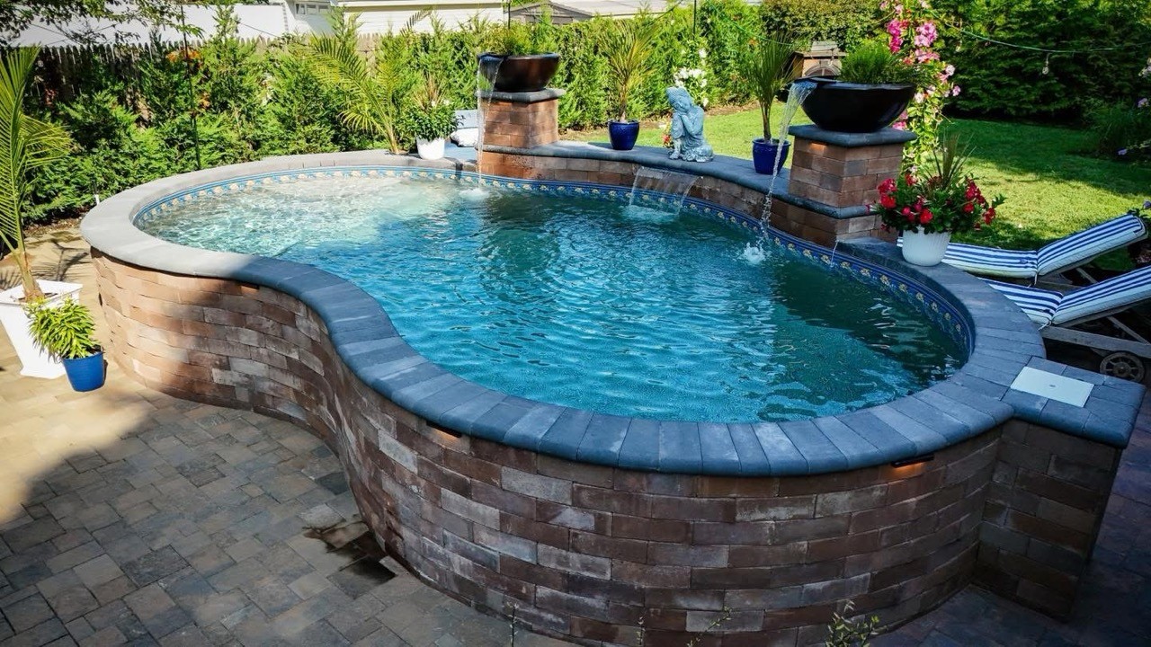 Raised curved pool and spa with stone veneer by CMC Masonry