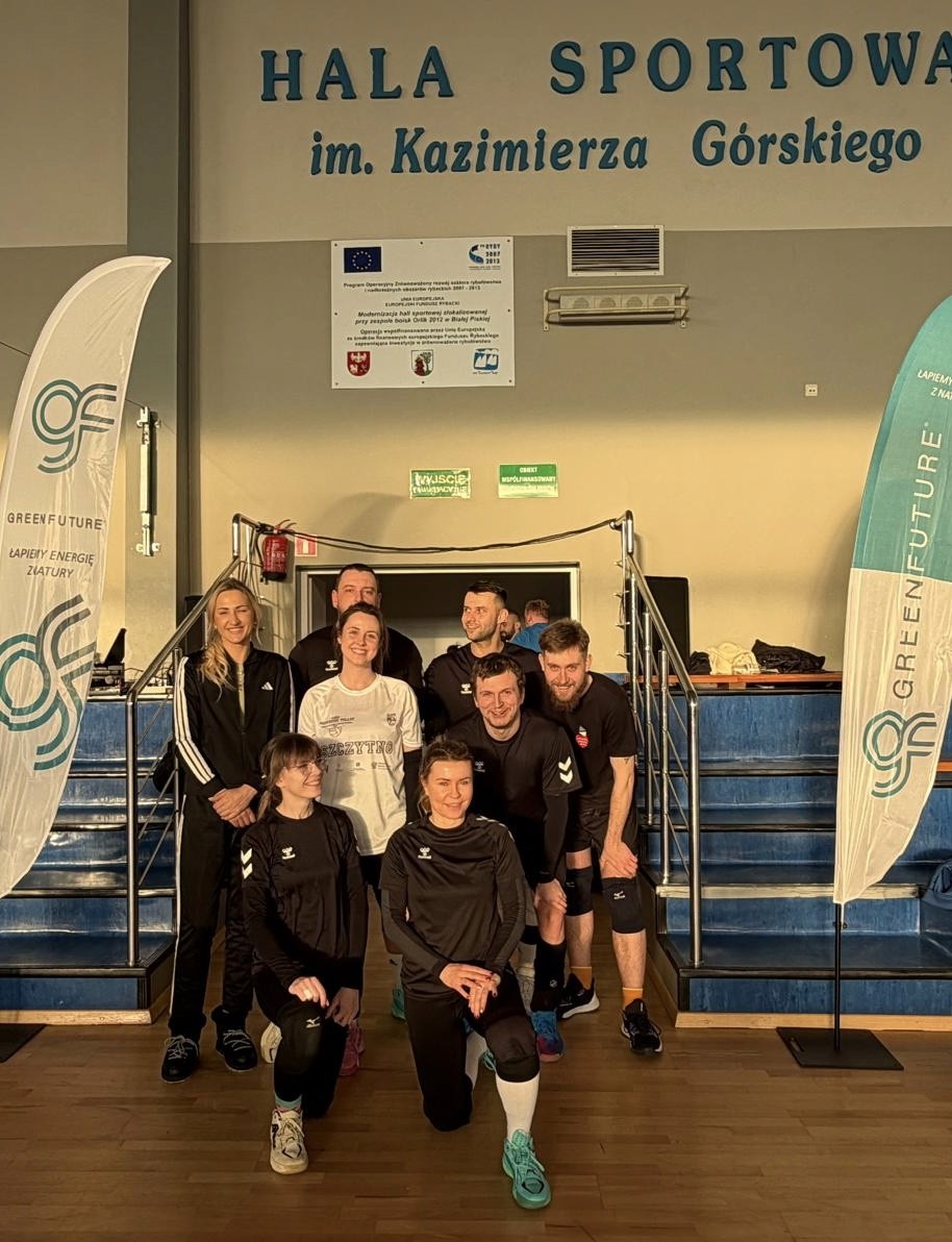 A woman with red hair in a lavender coat and scarf poses against a neutral background, showcasing a stylish and elegant look.