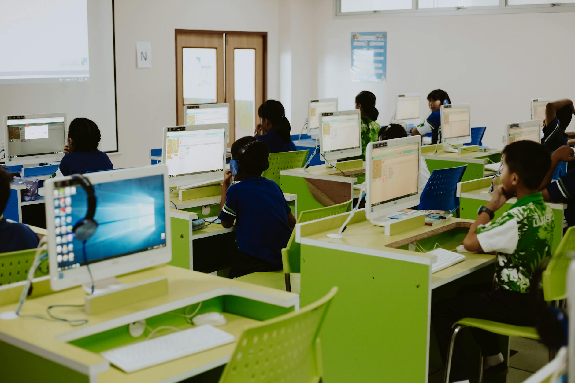 Split screen view showing a desktop computer lab next to a student using a laptop on a park bench.