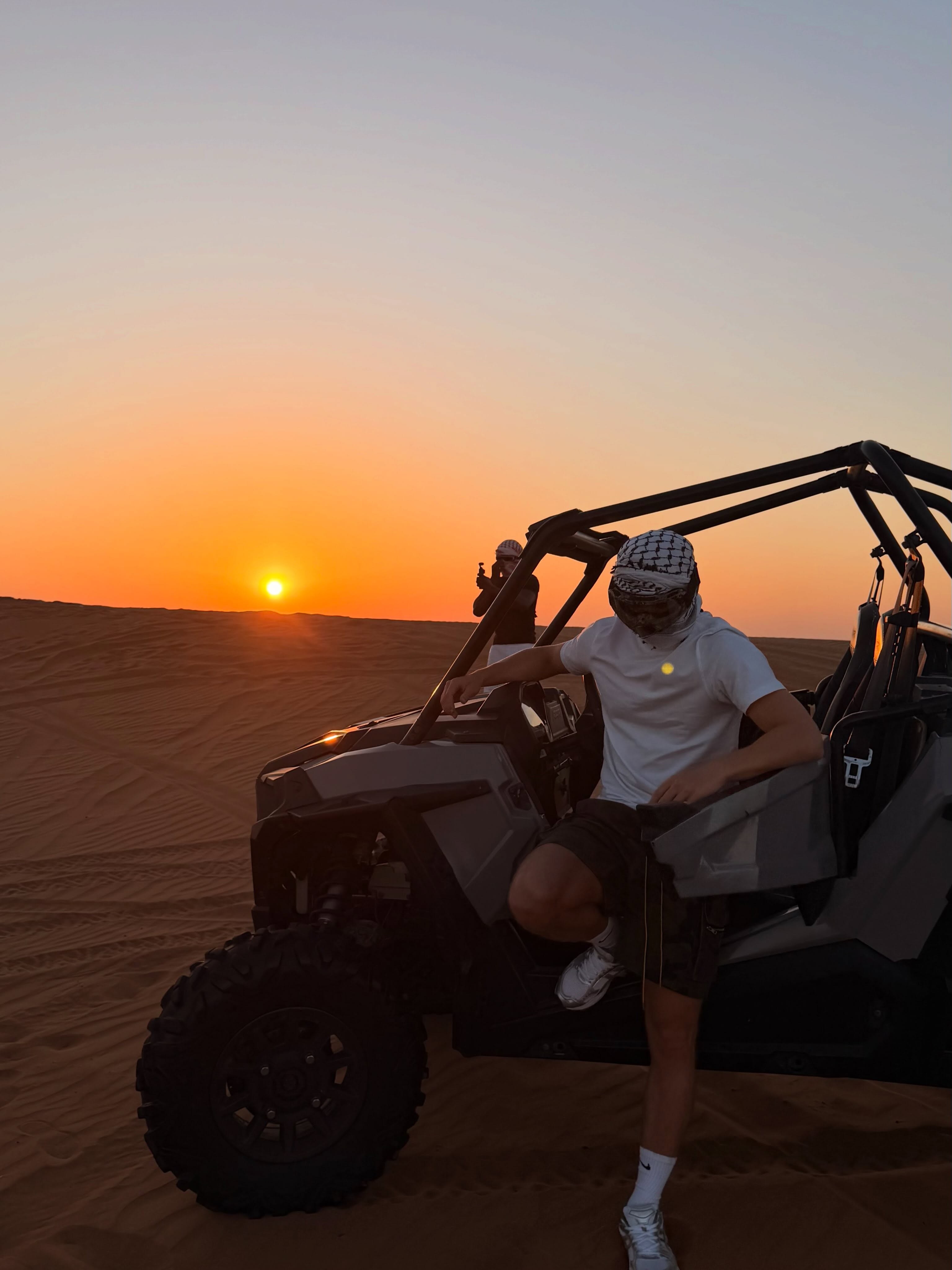 A female traveler smiling and cheering on a red quad bike during a desert safari excursion in Dubai