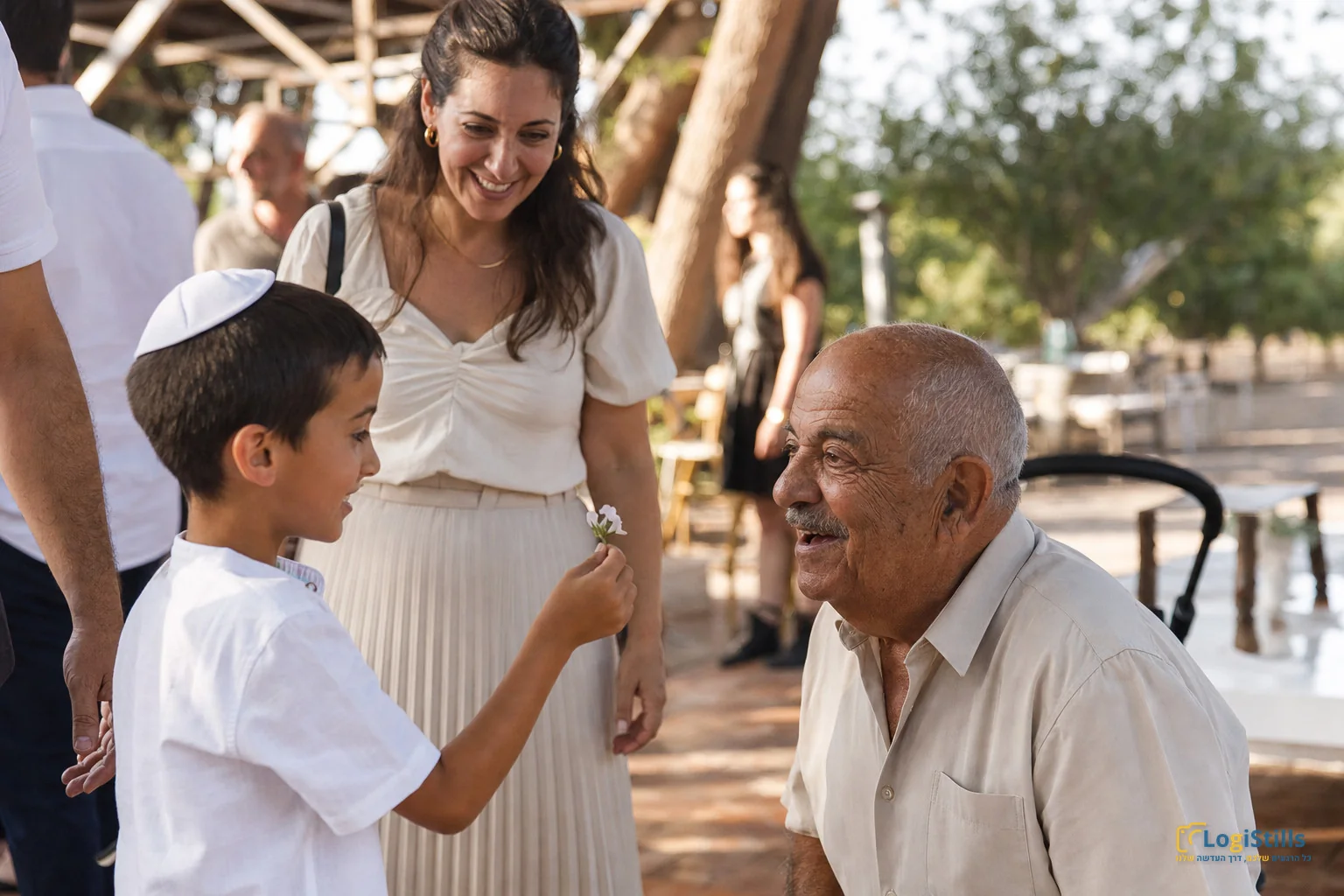 ילד עם כיפה לוחץ יד לסבא לצד אמו באירוע משפחתי