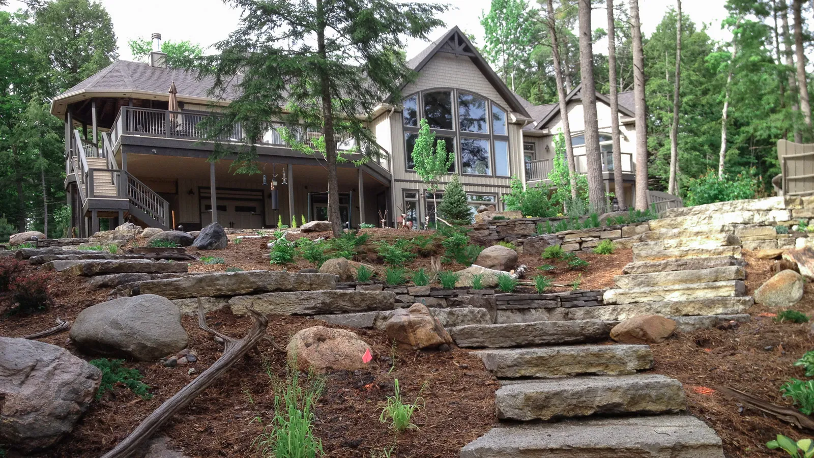 beautiful haliburton cottage with stone walled gardens and natural mulch pathway through the landscape.