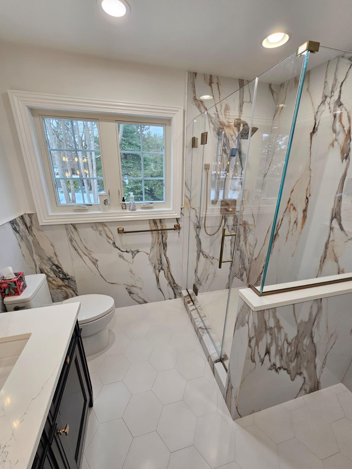 Bathroom renovation with marble tile walls, glass shower, and modern fixtures