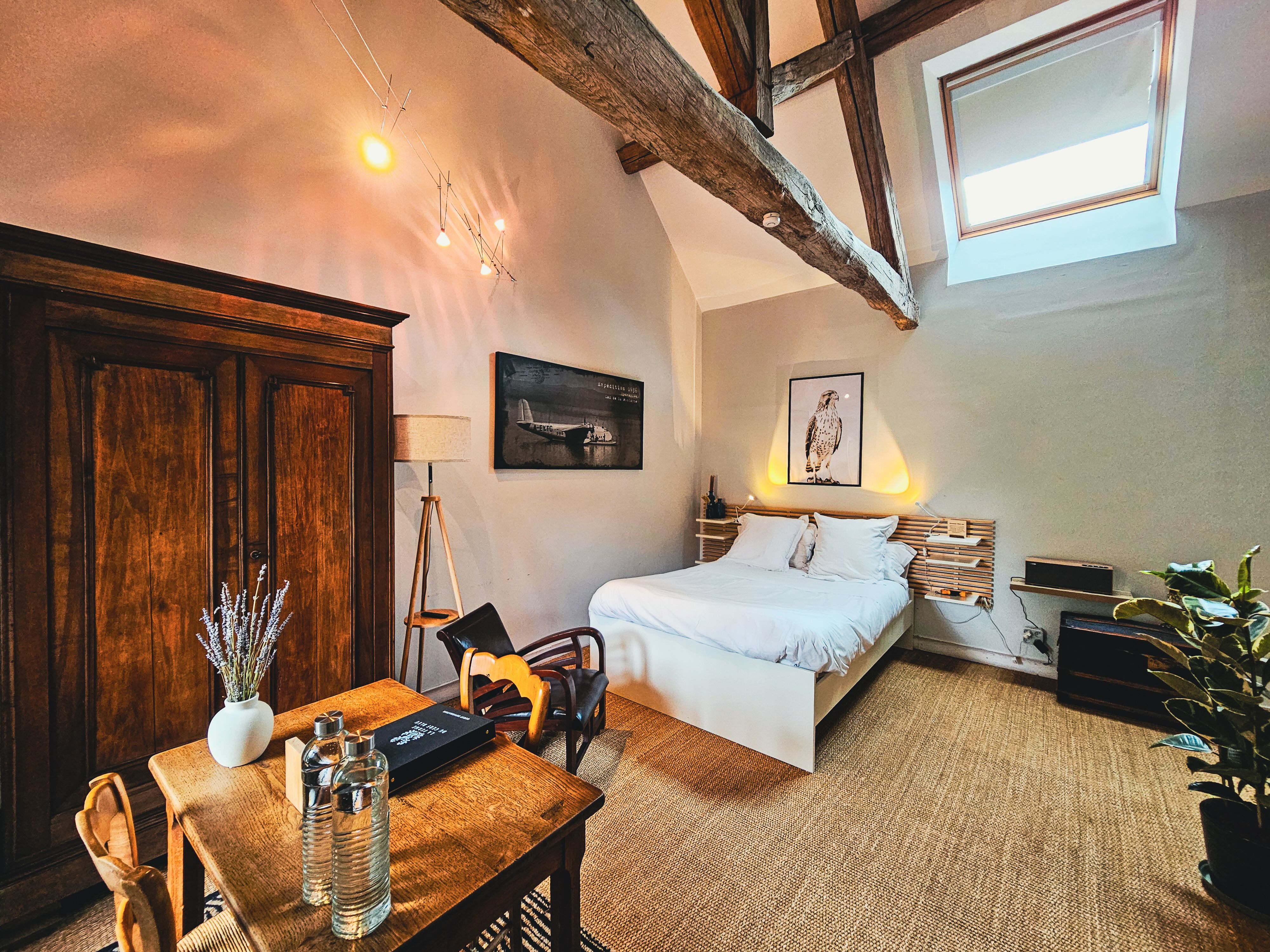 Chambre avec lit, armoire ancienne, tableau et lustre.