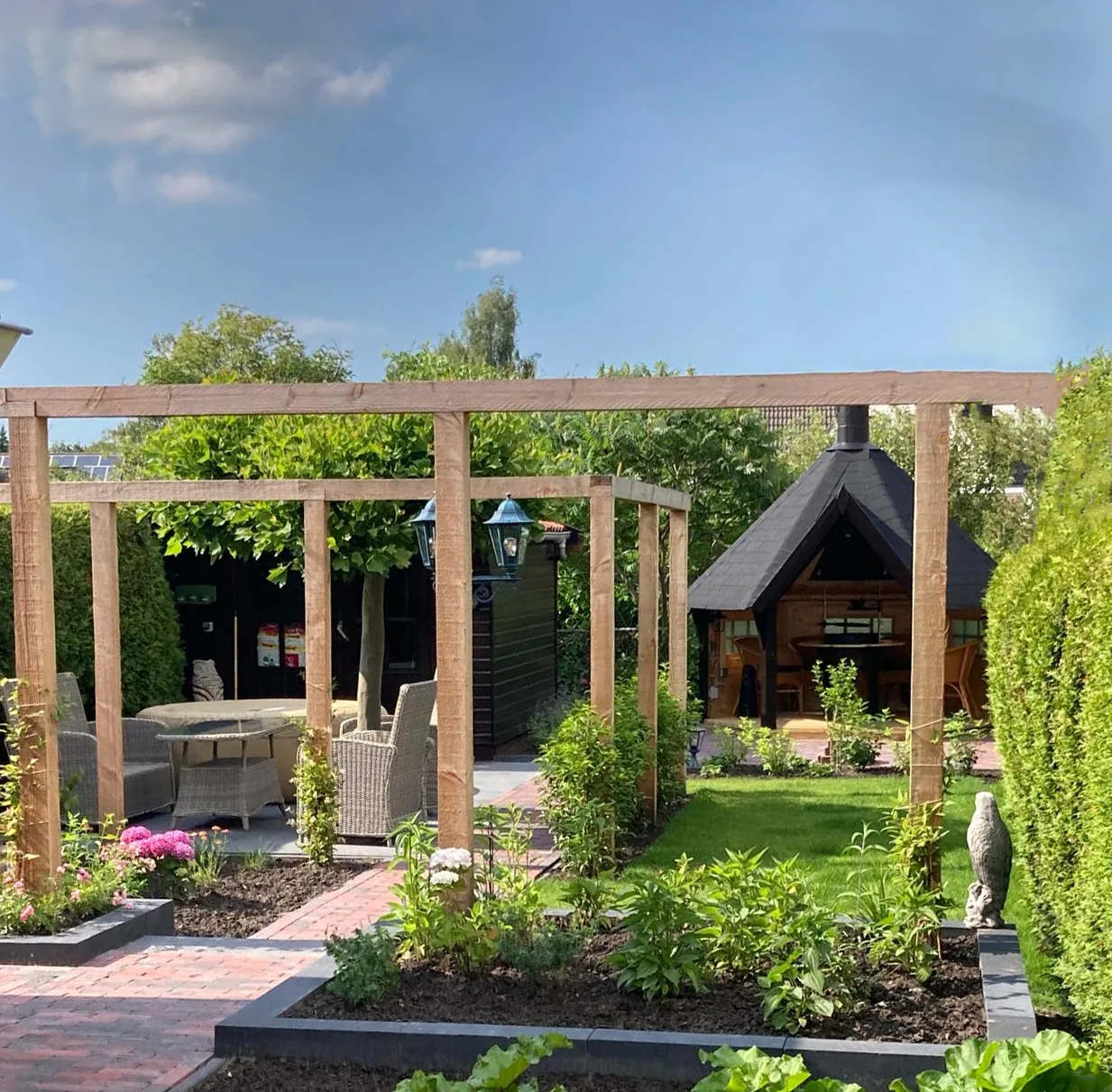 Tuin met houten terras en open loungebank, onderdeel van tuinaanleg in Gorredijk / Friesland
