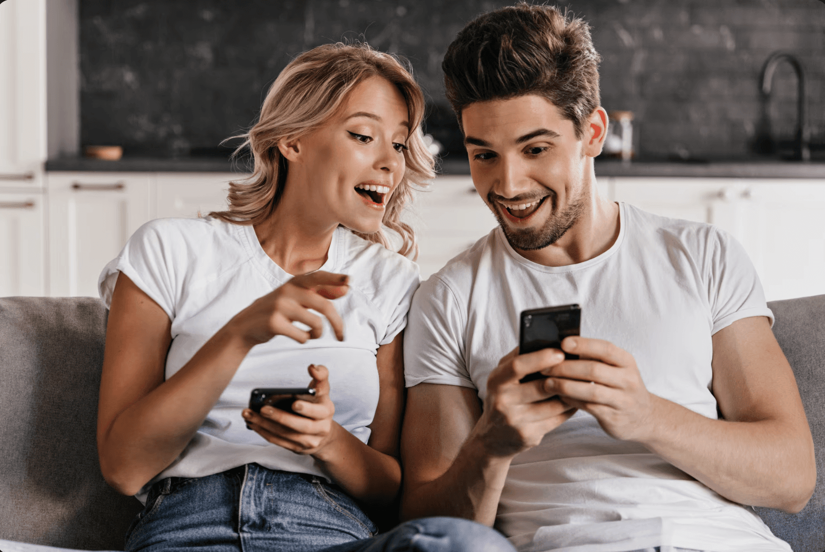 woman holding a phone and man looking at the phone. both are smiling