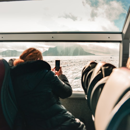 Человек фотографирует ледник Лангйокудль изнутри грузовика Слейпнир
