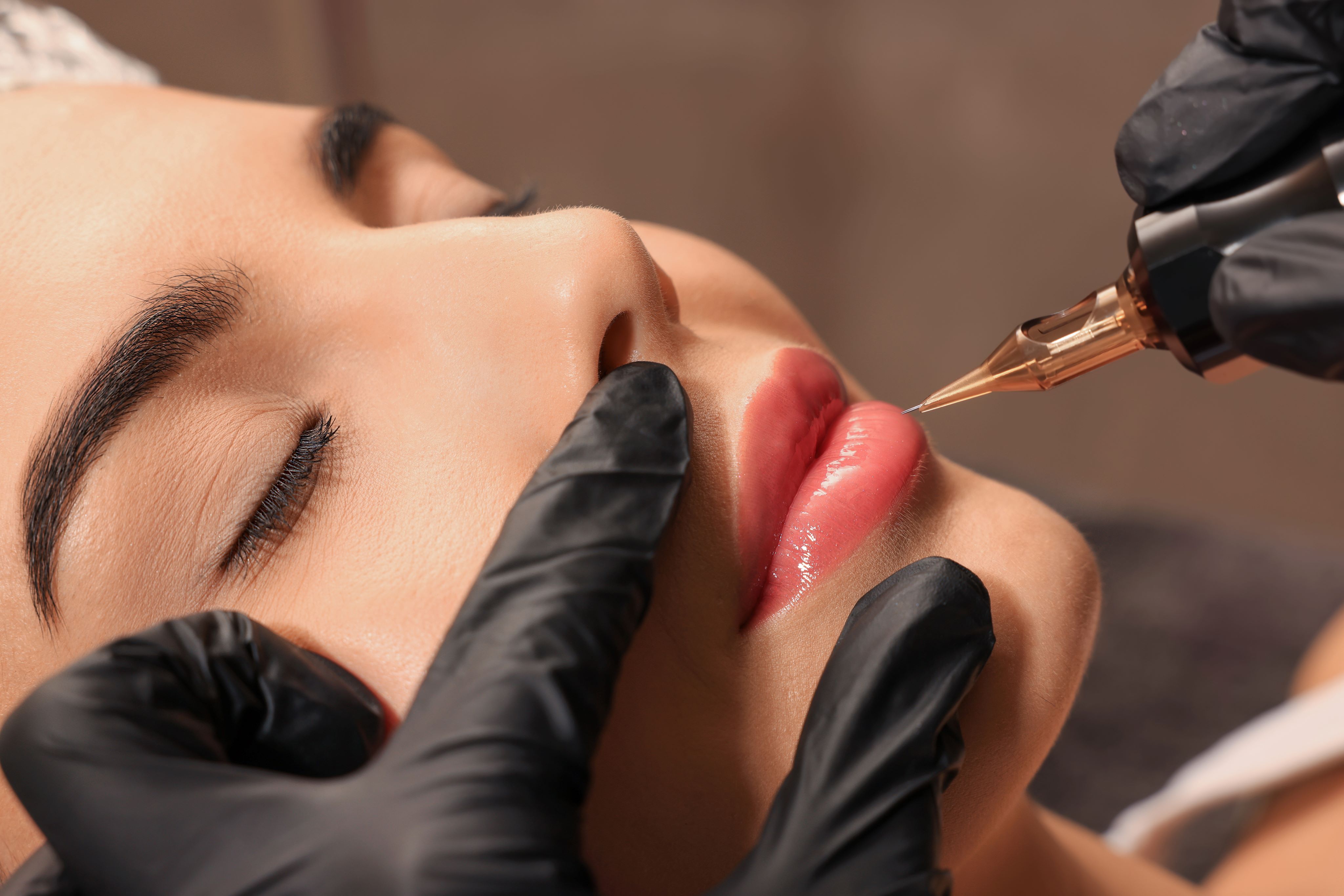 Woman receiving lip blush tattoo, enhancing natural lip color with permanent makeup.