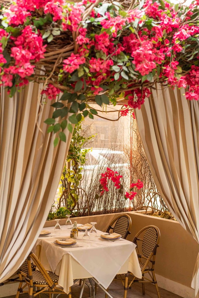 A cozy dining setup adorned with pink flowers and elegant drapes, creating a romantic atmosphere.