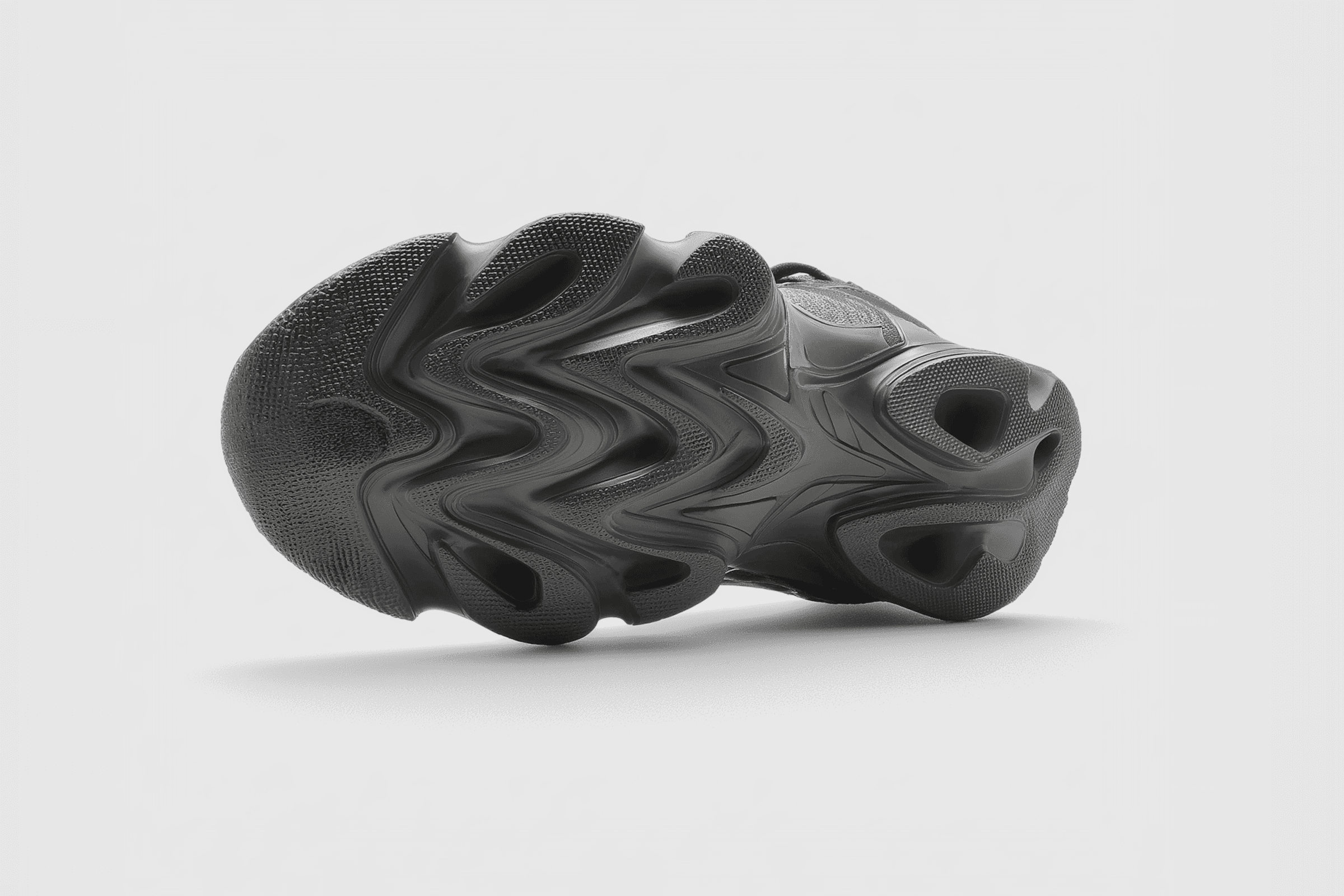 Close-up of a black athletic shoe sole with a wavy, textured design, showcasing its advanced grip and flexibility features.