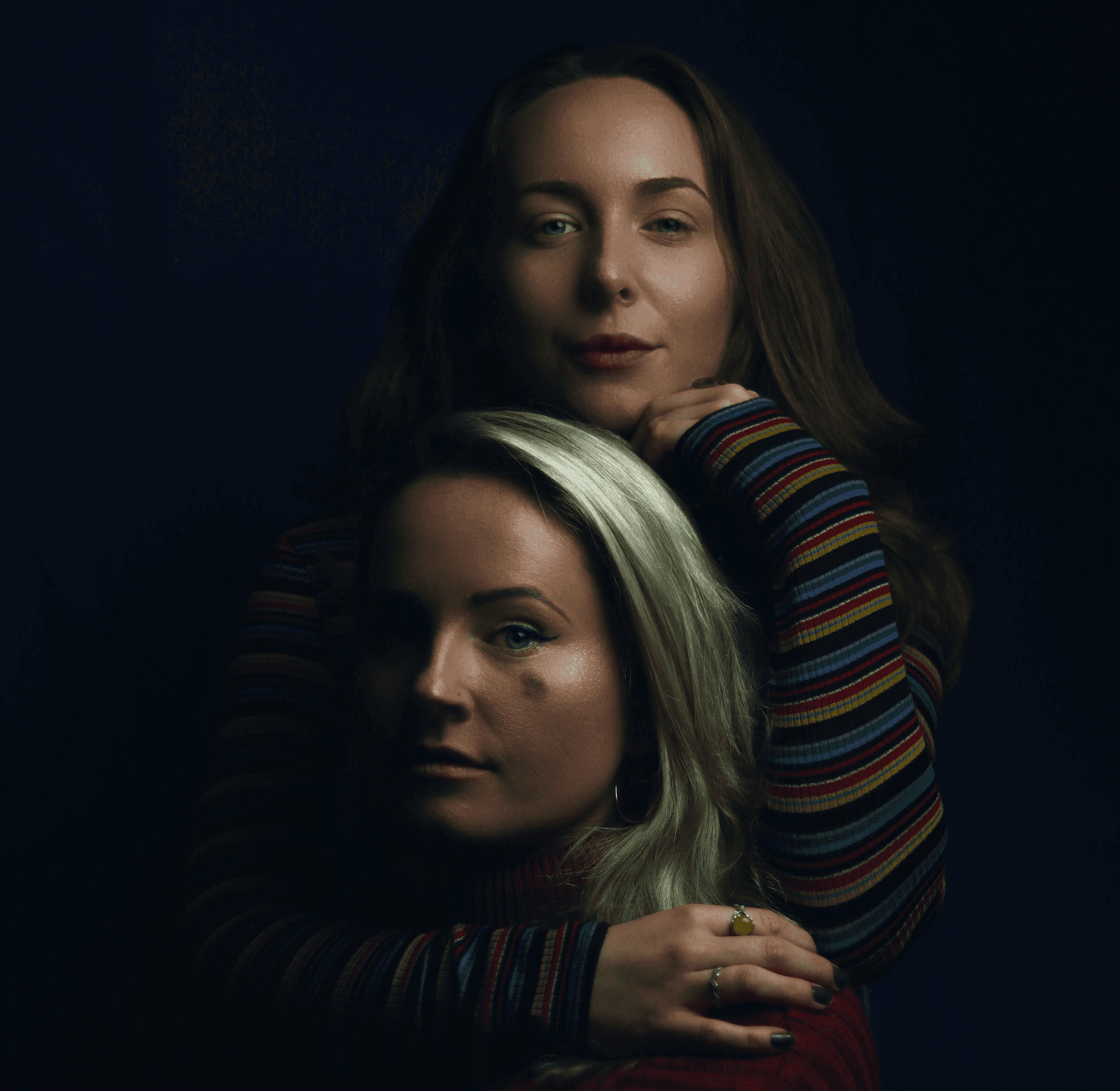 woman in striped shirt back hugging woman