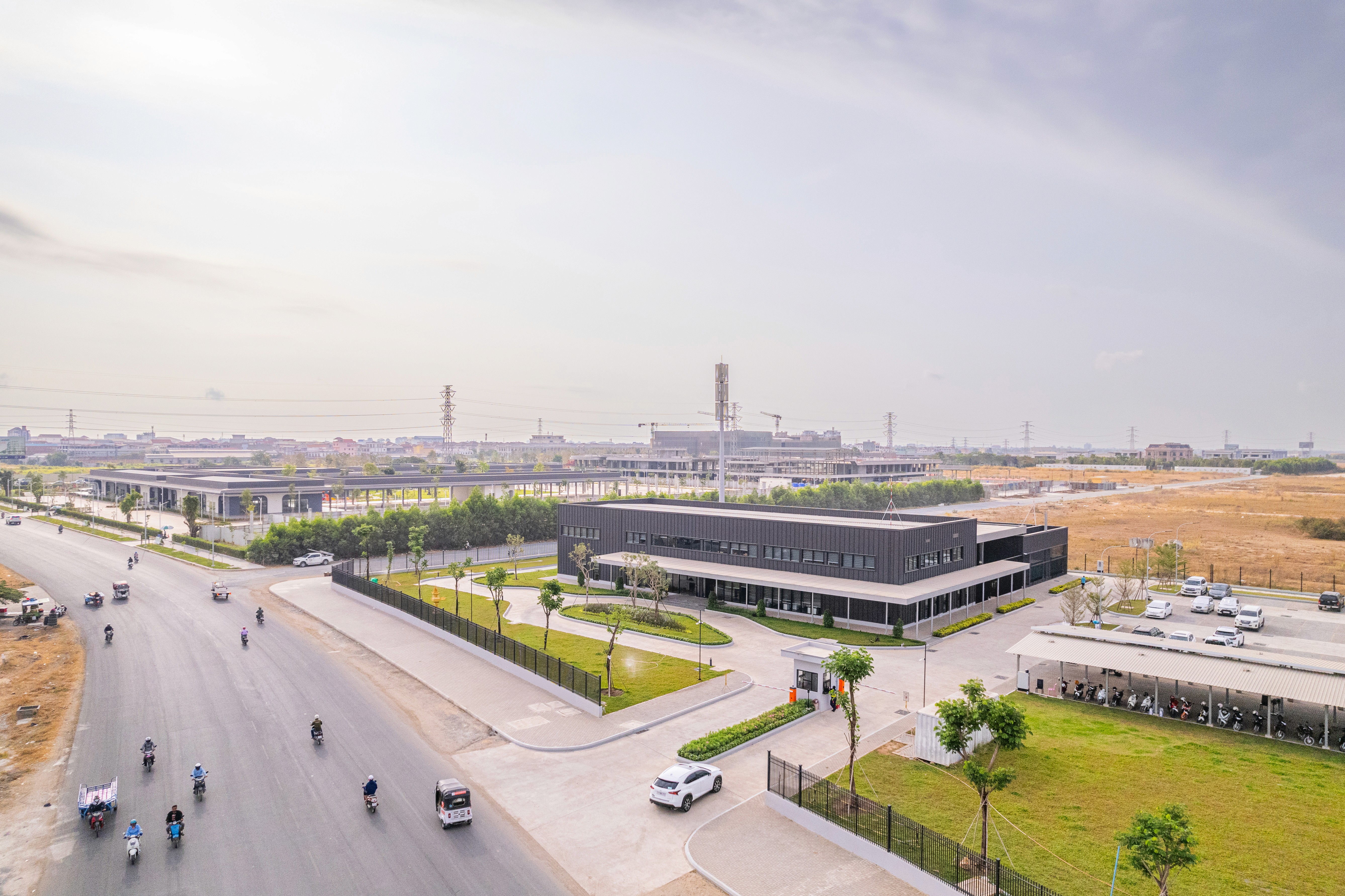 Wide aerial drone shot of the data center campus showcasing the modular building form, secure entry gatehouse, and integration with the surrounding urban infrastructure and arterial road network