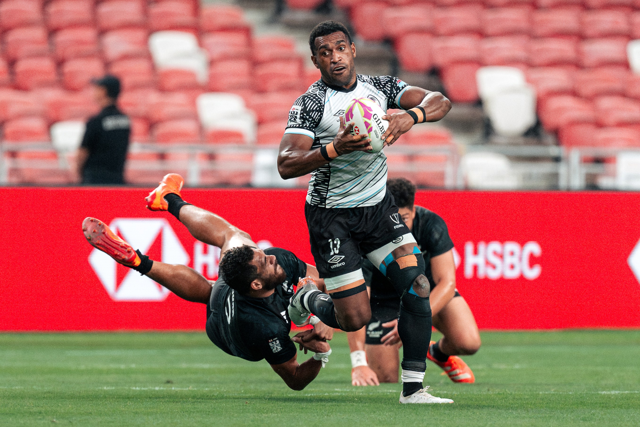 Joji Nasova escapes a challenge by a New Zealand All Blacks player during a match at the HSBC SVNS Singapore 2025