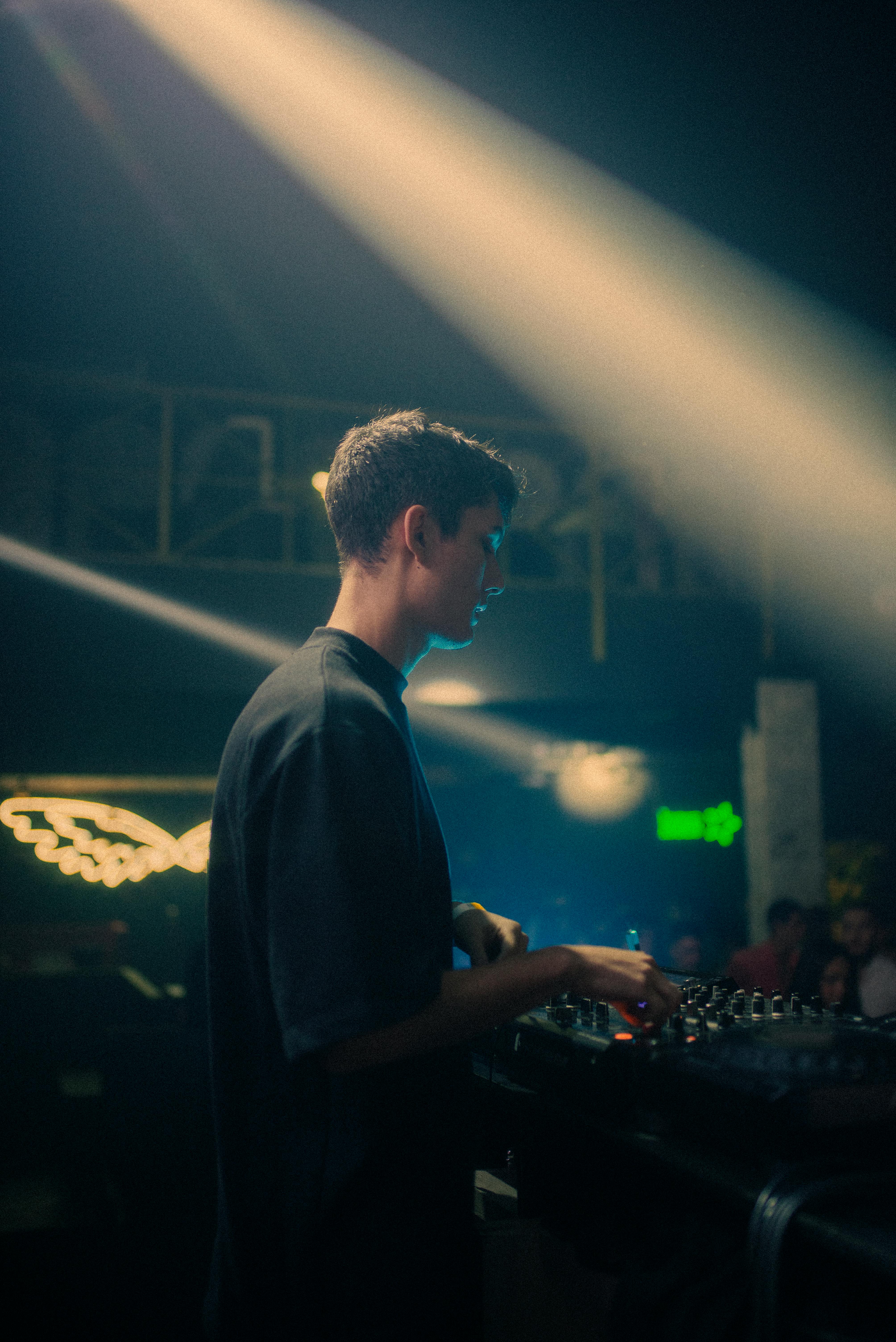 A person wearing headphones tilts their head back against a plain beige background.