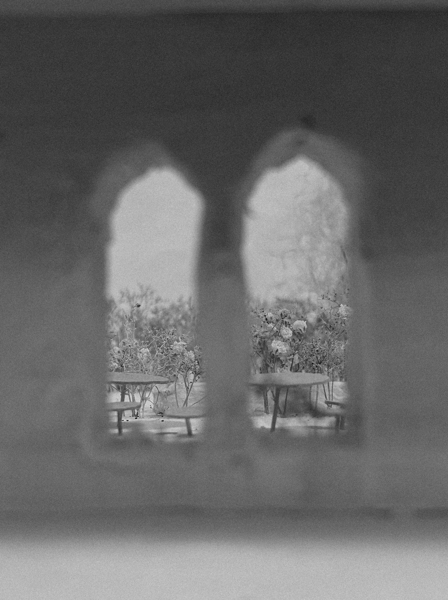 Two arched windows are framed against a hazy background, hinting at a scenic landscape outside.