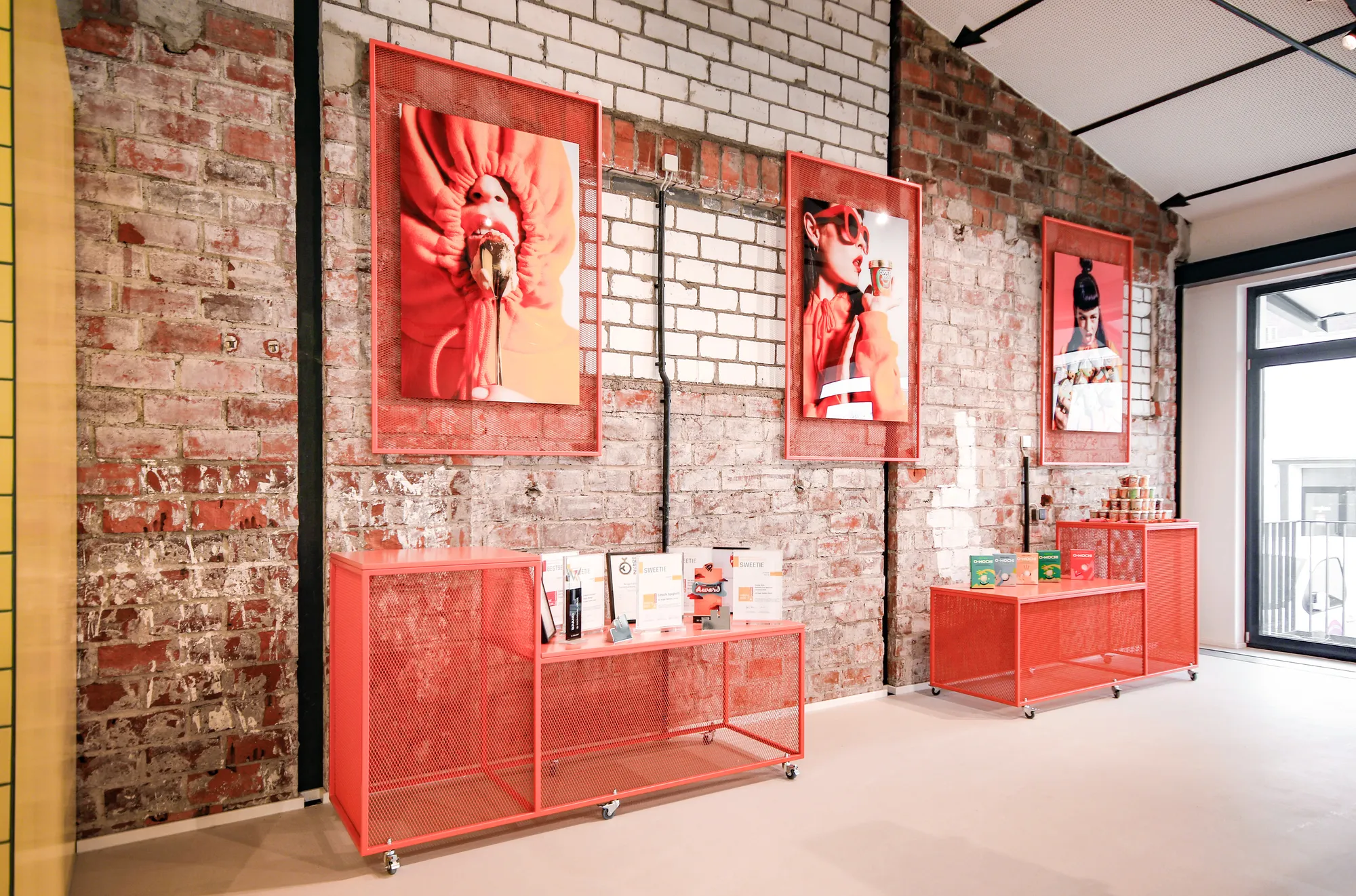 Red metal shelves and framed food photos along the exposed brick wall.