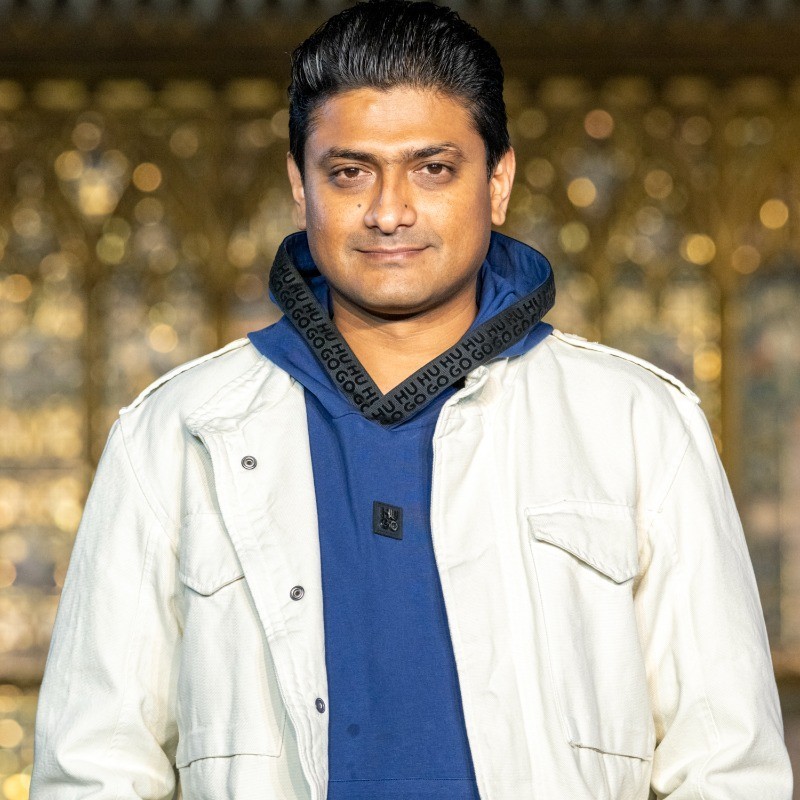 A person wearing the grey coat smiling in a cozy sunlight