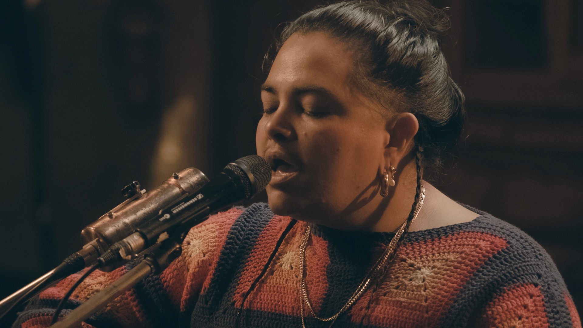 Close-up portrait of Mo'Ju singing passionately into a microphone