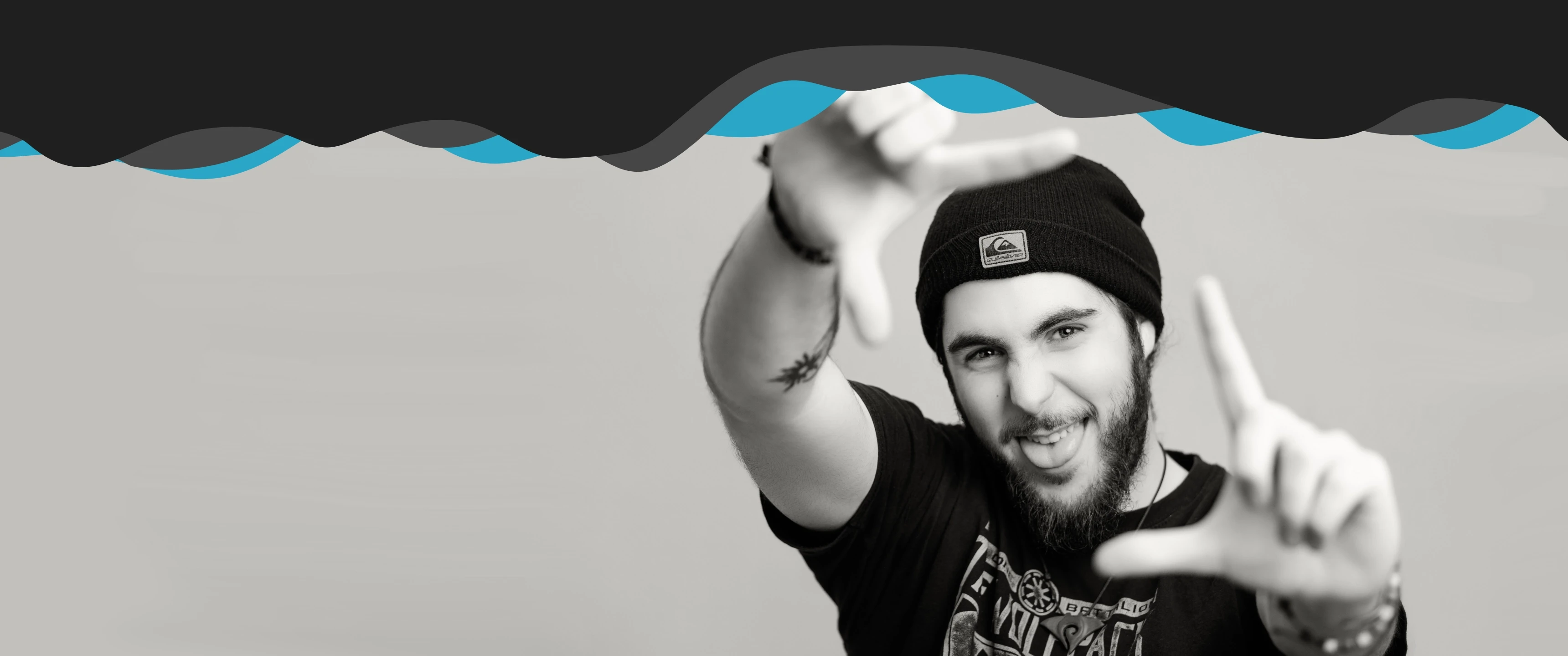 Black and white portrait of videographer framing a shot with hands against a clean background, representing creative direction, visual storytelling and professional videography by Raybrand Media