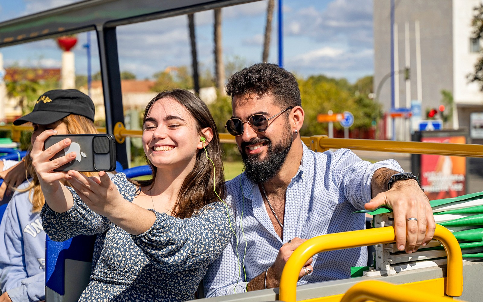 Personas tomándose una selfie en un autobús de paradas libres en Sevilla con los monumentos emblemáticos de la ciudad de fondo.
