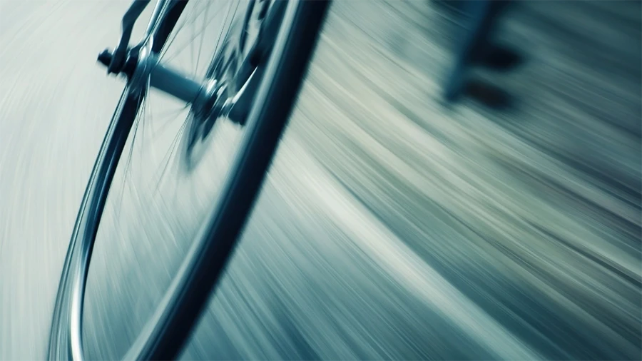 Close-up motion blur of a bicycle wheel in motion, symbolizing speed, agility, and forward momentum.