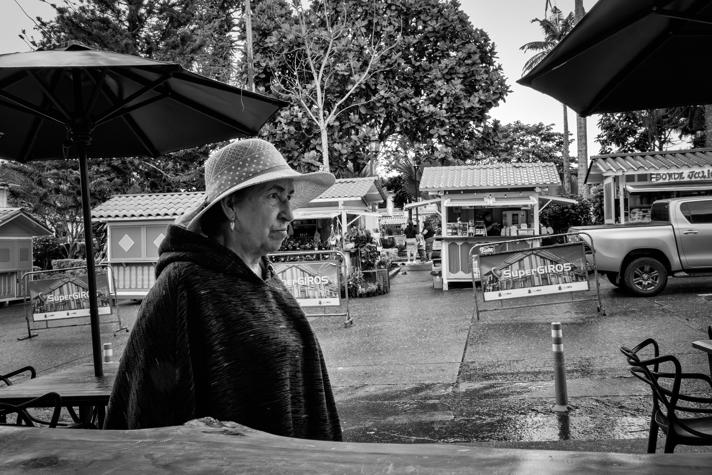 Rainy street scene with people passing by a bar window.