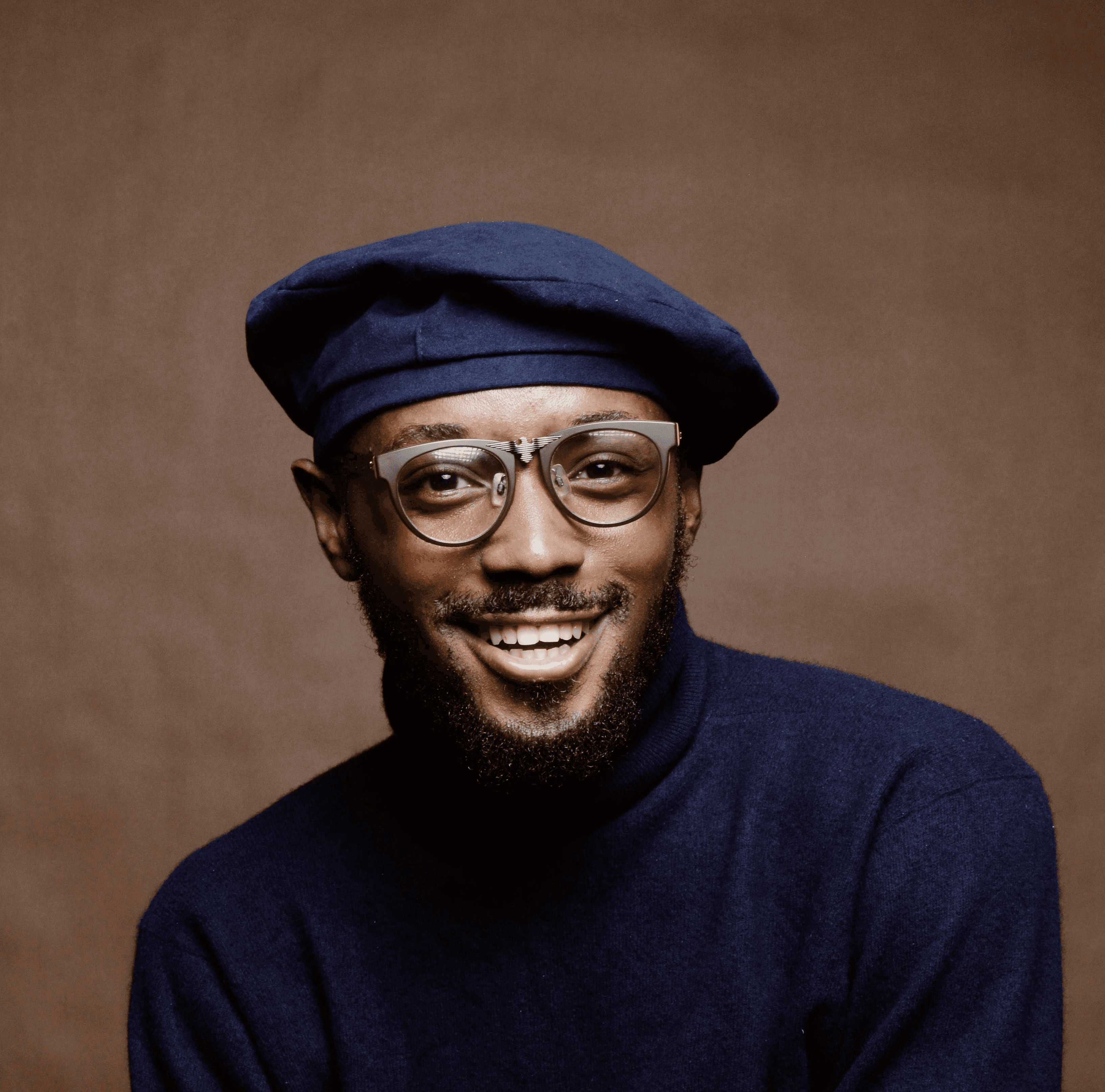 smiling man wearing black turtleneck shirt holding camrea