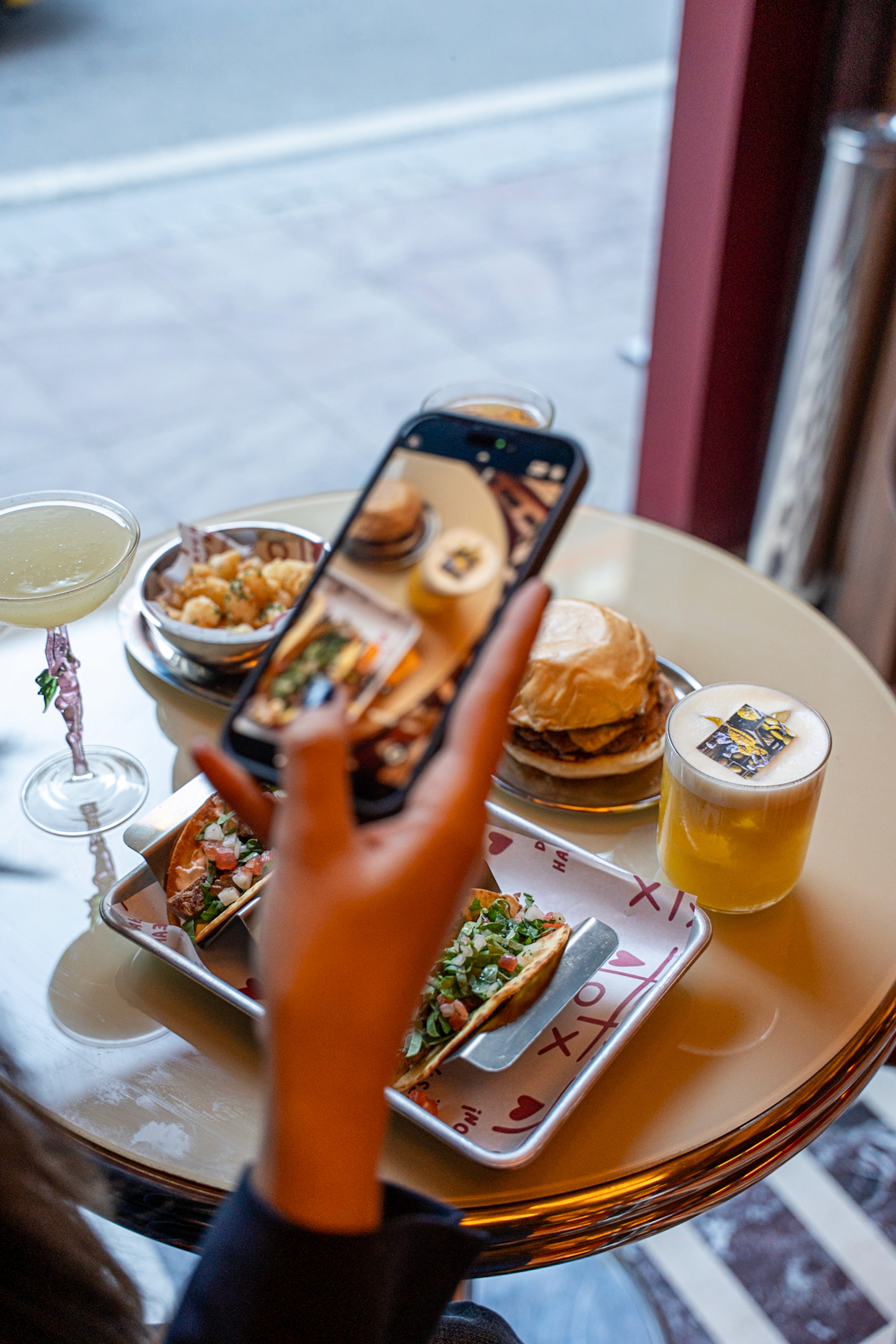 Wooden sauna cabin and hot tub set among rocky mountains and greenery under clear sky.