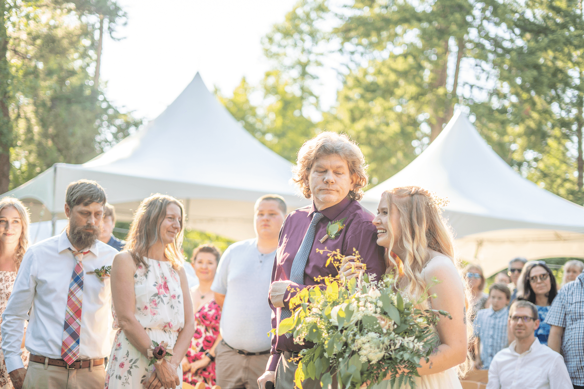  a bride walking with her father down the aisle towards her groom, tearing up