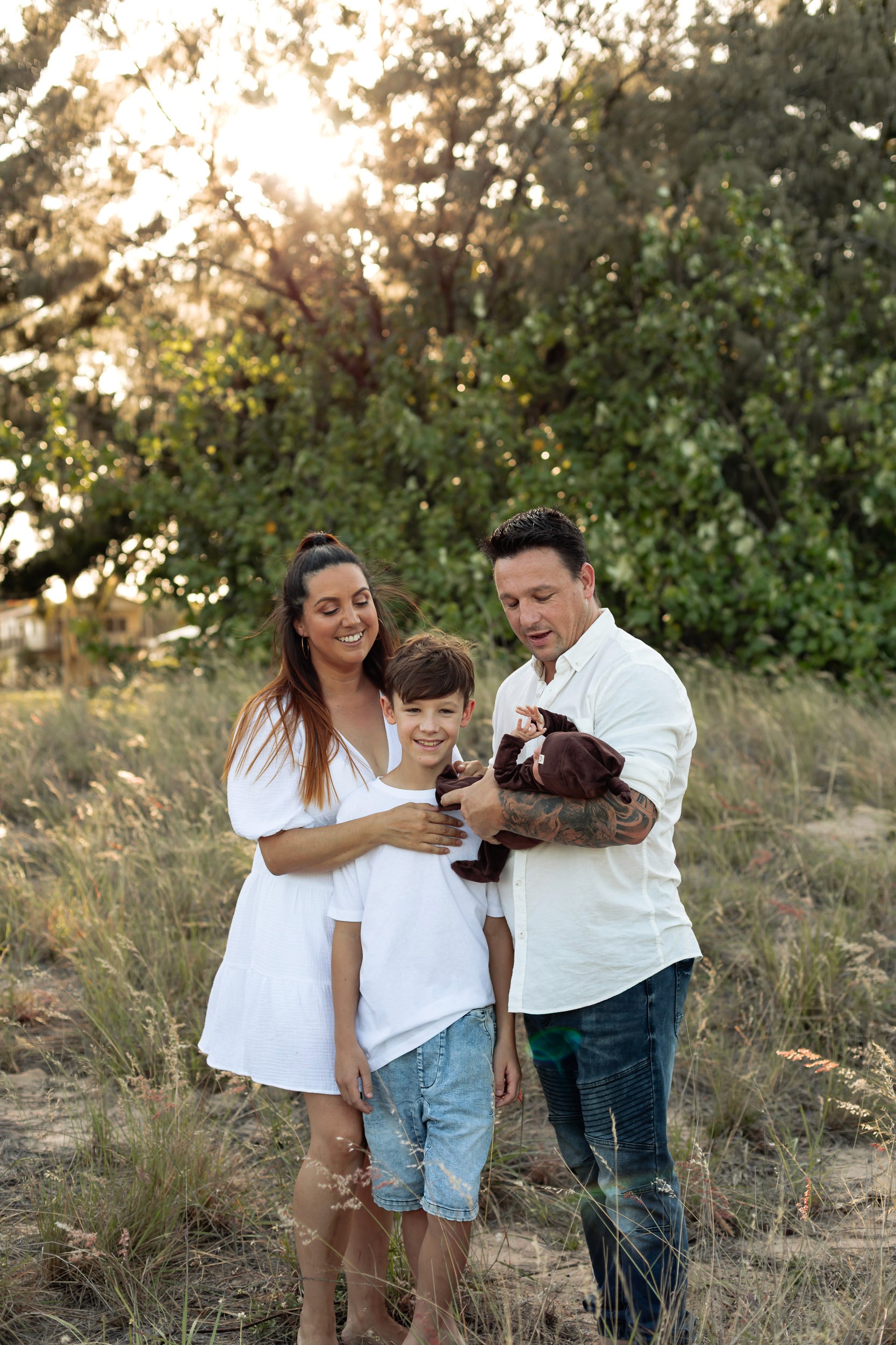Baby with parents and sibling in front of the setting sun