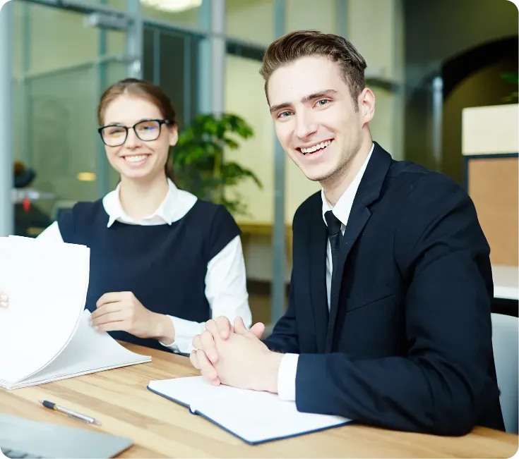 Two business professionals smiling during a certification meeting in a modern office.