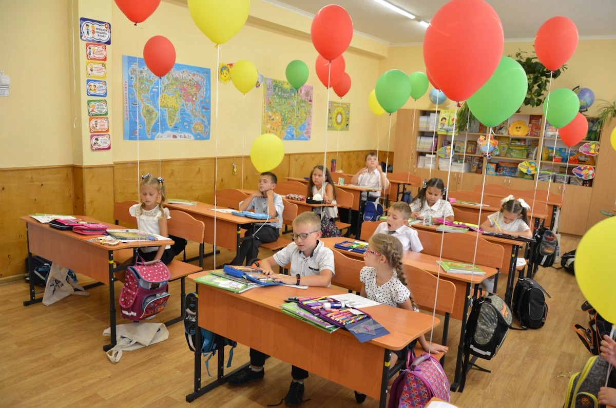 Children sitting at desks in a decorated classroom.