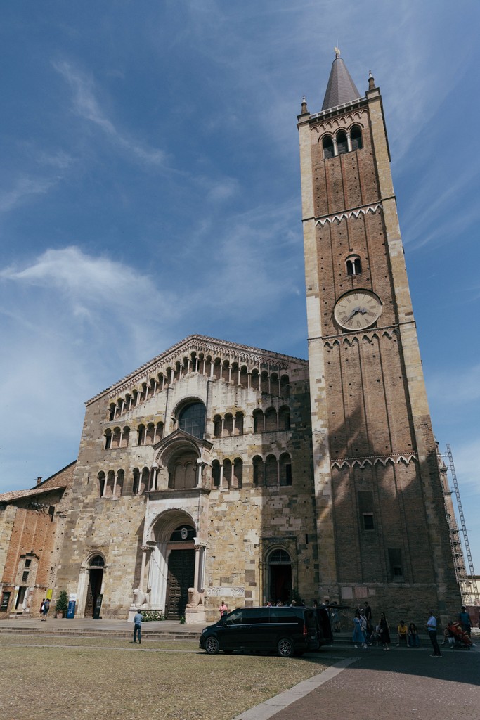 Facciata della chiesa di Cremona con campanile e orologio, piazza antistante con visitatori in luce diurna