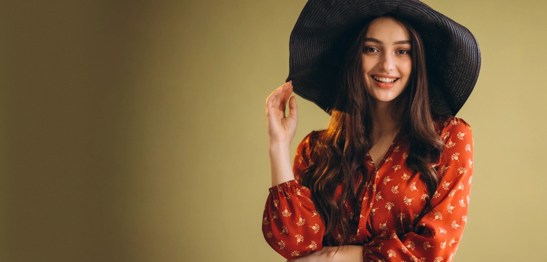 Model in a red patterned dress wearing a wide-brim black hat