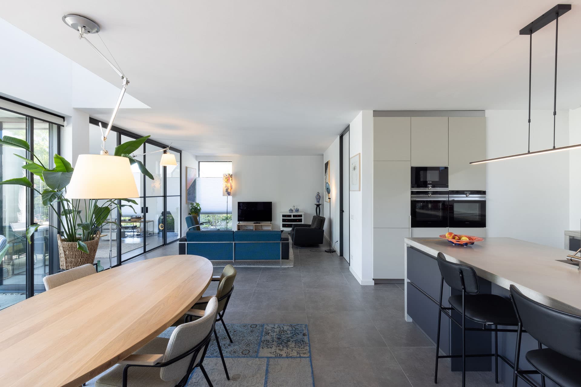 Open woonkeuken van Villa Rijswijk met kookeiland, eettafel en grote glaspartijen naar de tuin.