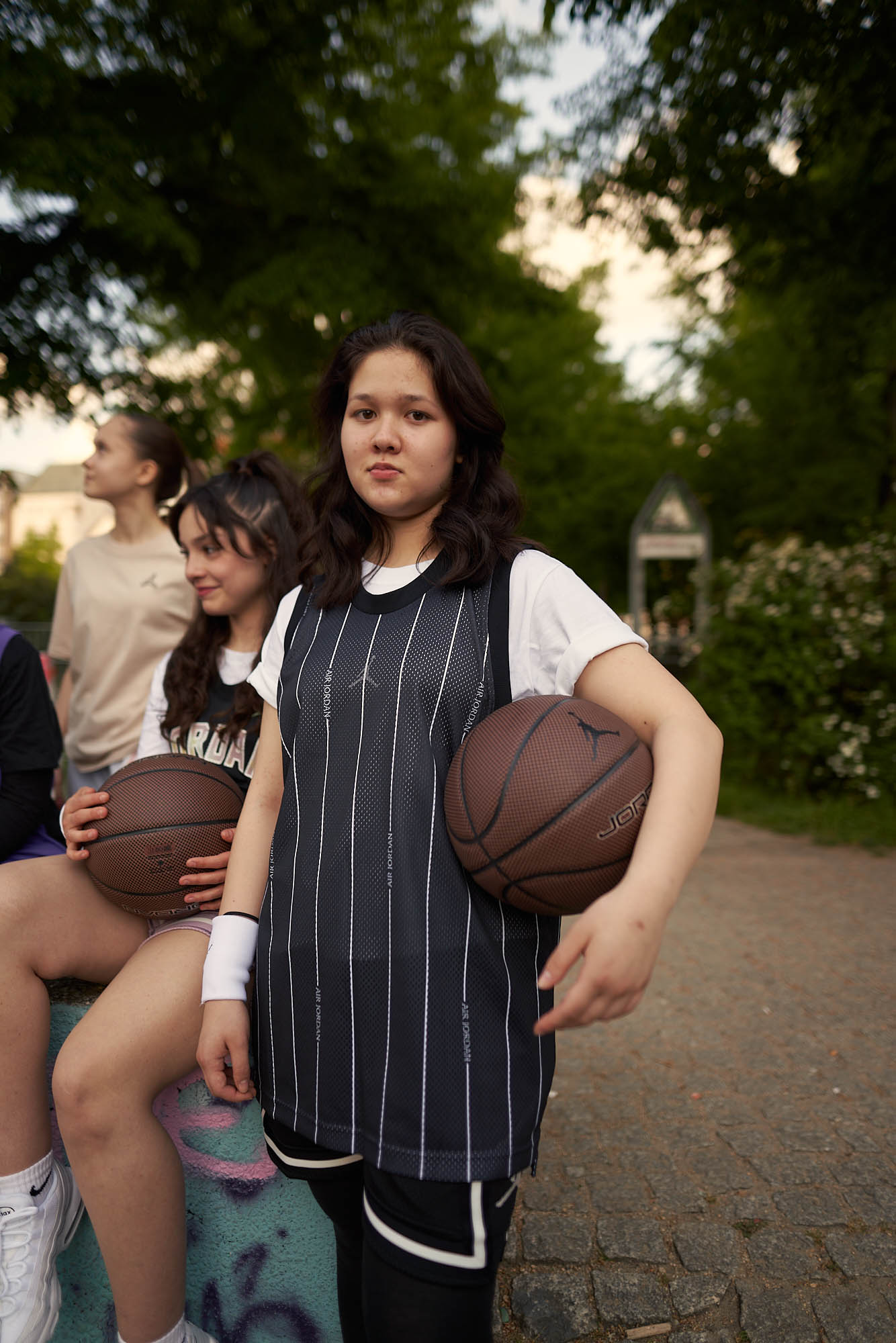 Person with basketball jersey, holding a basketball under their arm